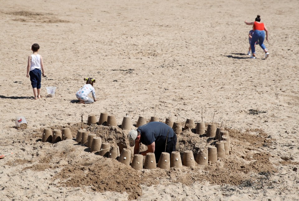 A man builds sandcastles on the beach this afternoon