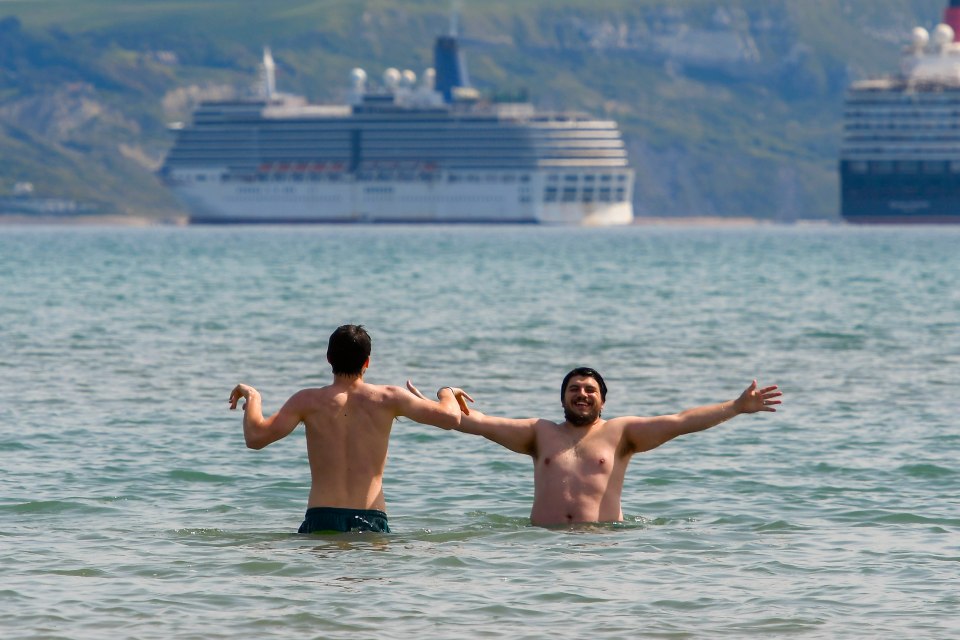  Two friends enjoy a dip in the sea at the seaside resort of Weymouth