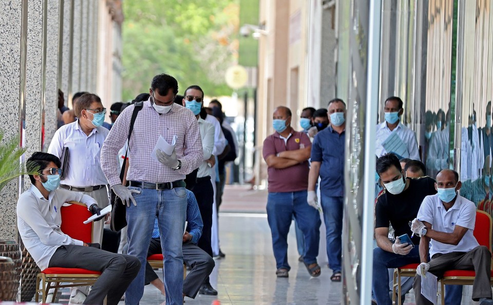 Men in masks wait in a queue in the Qatar capital Doha