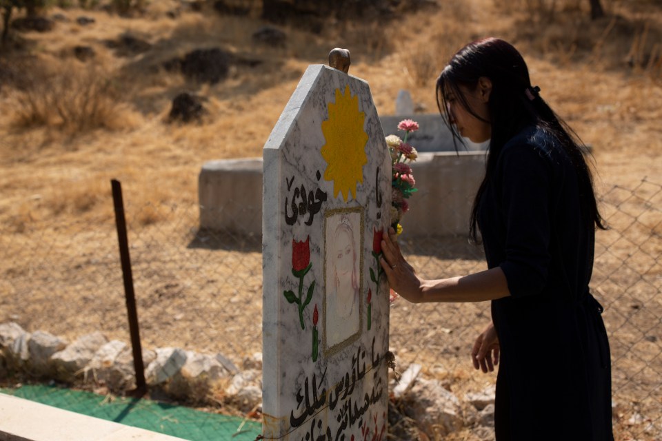 Ms Taloo, seen at the grave of a Yazidi woman who took her own life, is campaigning for justice for the ethnic and religious minority