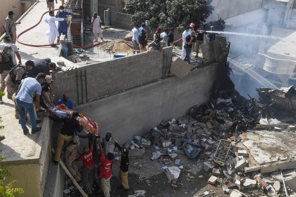  Emergency workers try to put out the crash fire with water as bodies are carried away