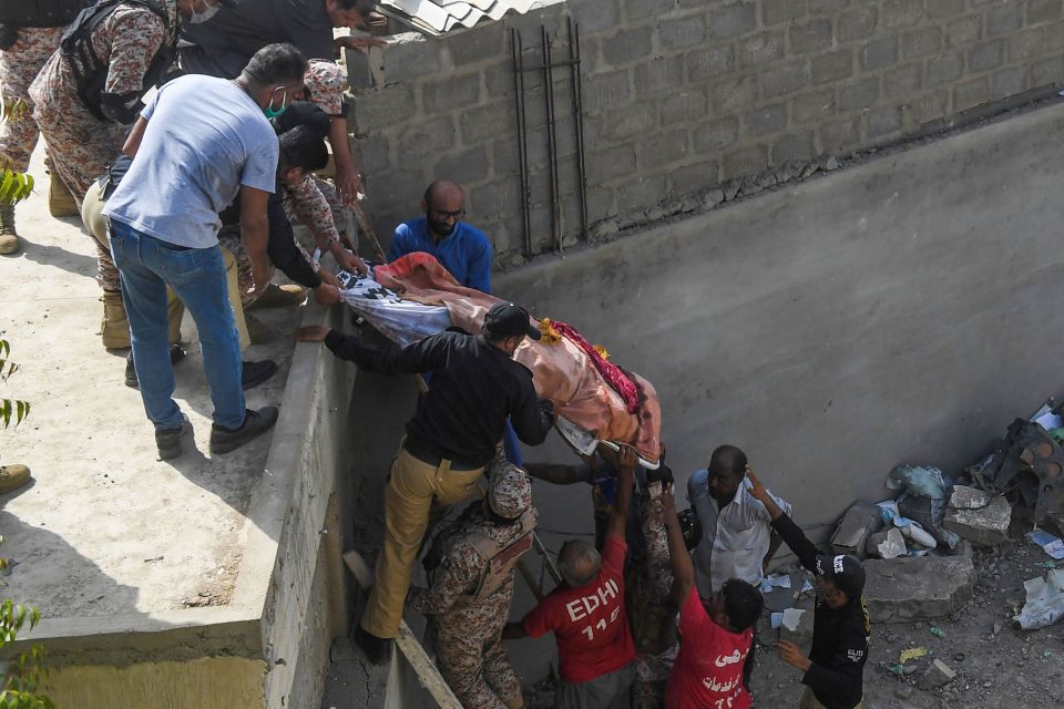  Emergency workers carry a body away from the wreckage