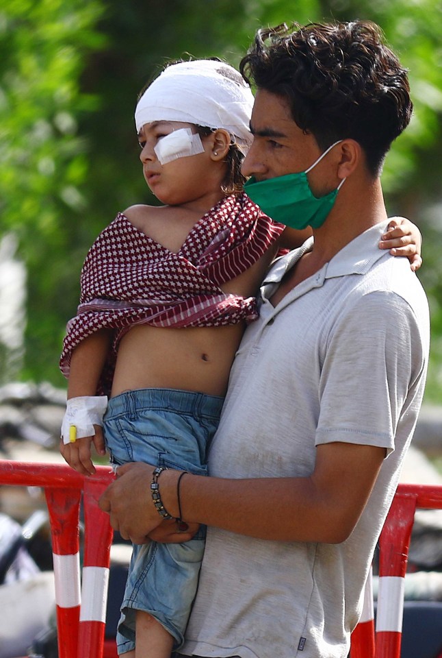  A child, apparently injured when the jet crashed into the residential area, watches on with his father