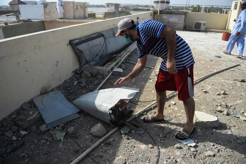  A man finds some wreckage on a rooftop in Model Colony