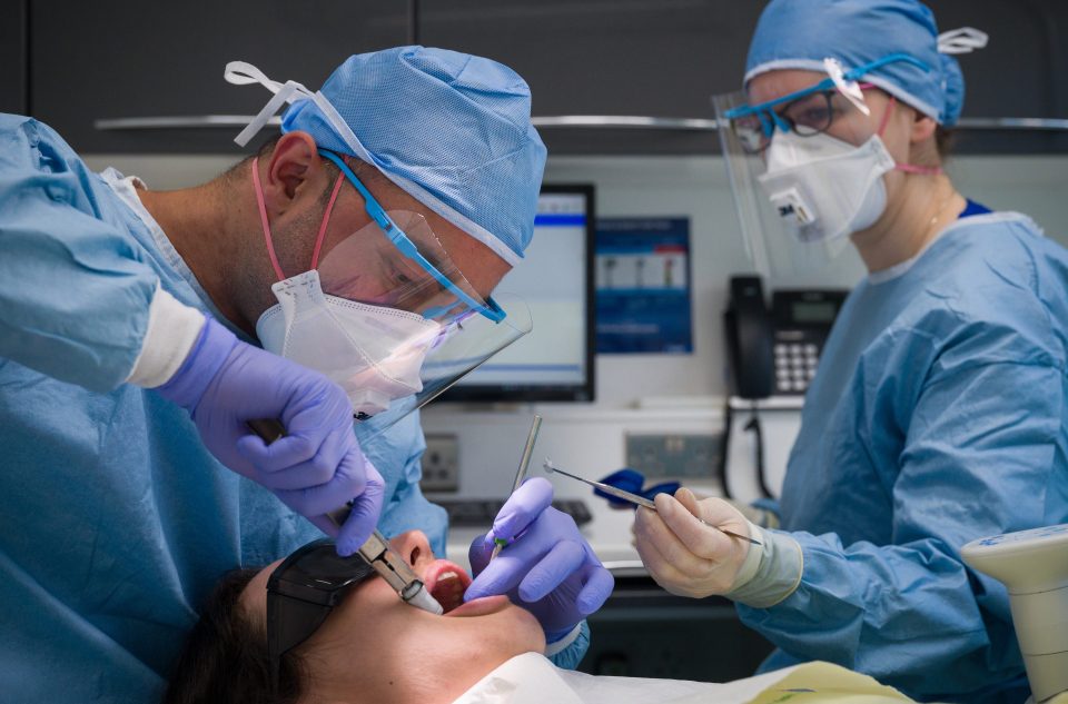 Dentists carry out a procedure on a patient in one of the six surgery rooms at East Village dental practice in London on June 8