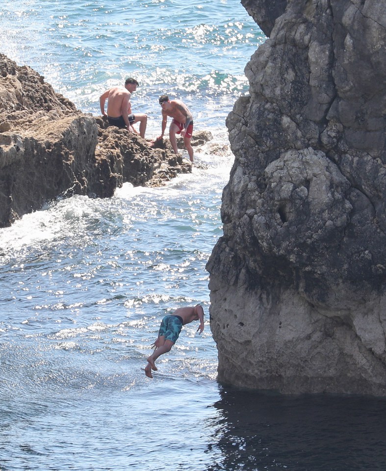 A person jumps into the sea from Durdle Door yesterday – despite three people being seriously injured