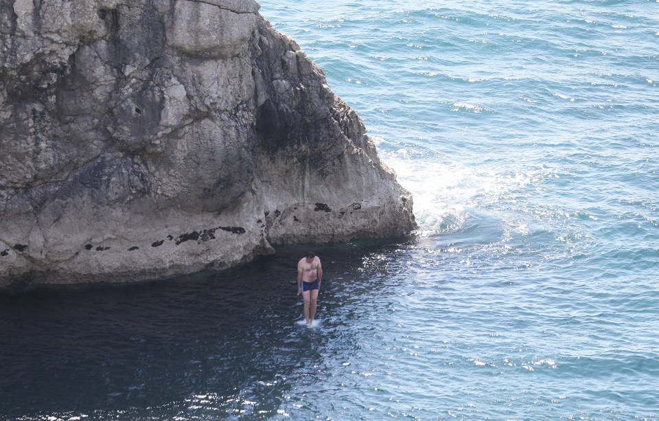 A person lands in the sea after leaping from the cliff