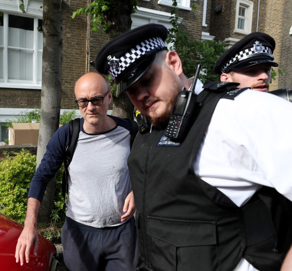 Dominic Cummings is helped to his car by police