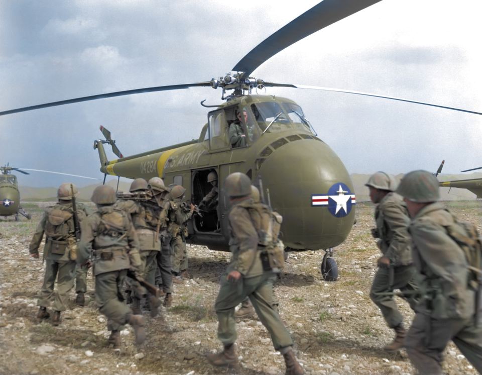 A group of American troops rush to their helicopter