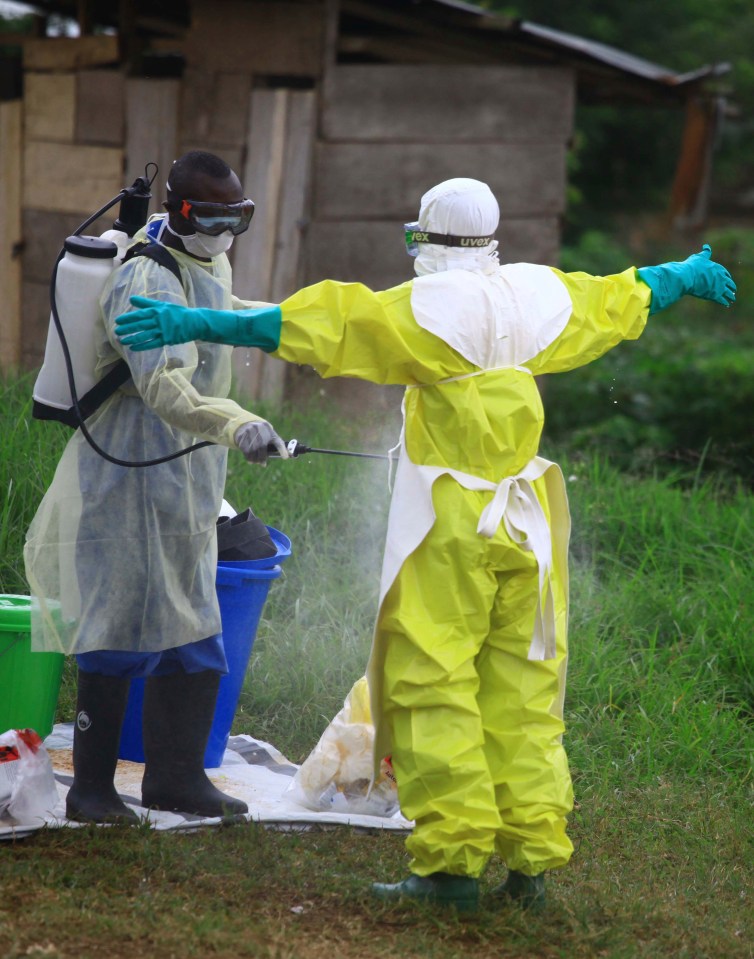  A health worker sprays disinfectant on a colleague treating Ebola patients