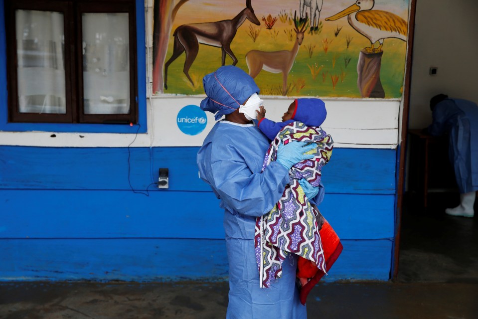  An Ebola survivor who works as a caregiver holds a baby