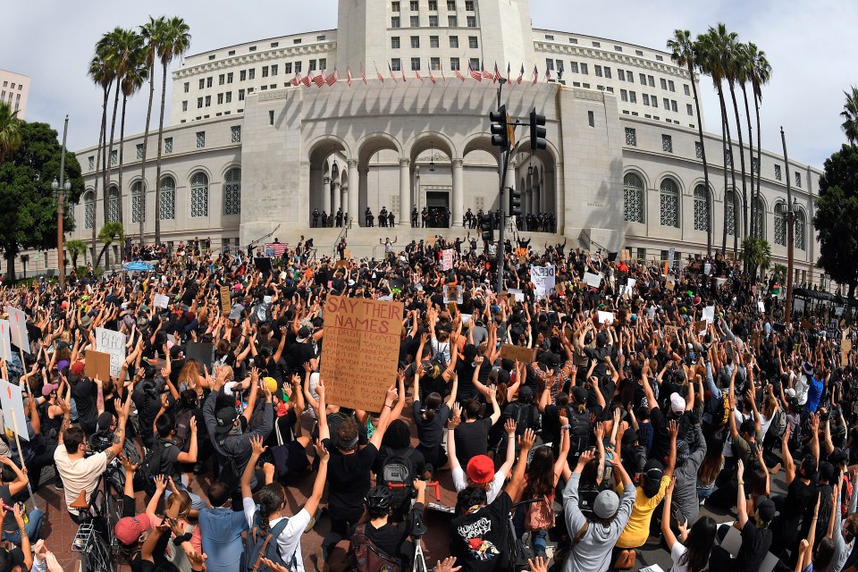 Demonstrators kneel in front of Los Angeles City Hall while giving a 'hands up don't shoot' gesture over the death of George Floyd