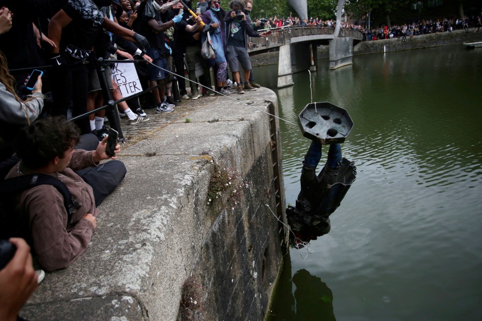 The statue is pictured being dropped into the river on Sunday