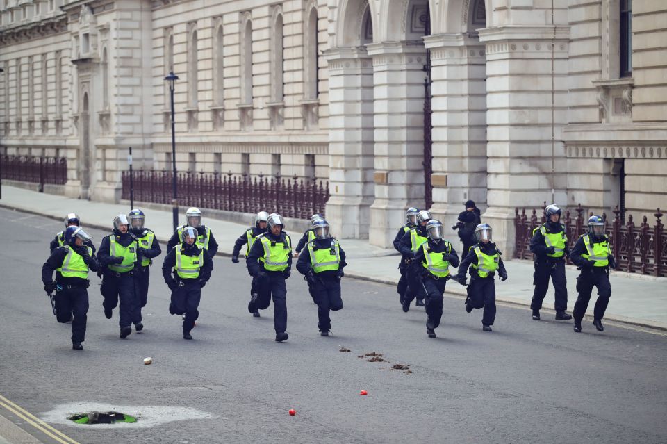  Police in riot gear race towards the thick of the demonstrations