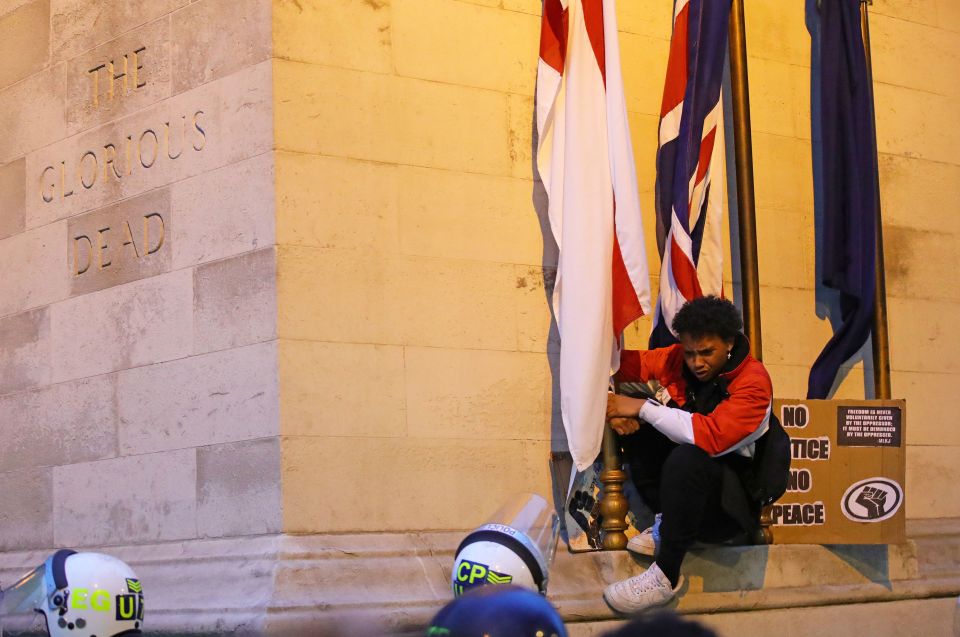  The woman clings on to the flag as she stands on the war memorial in Westminster