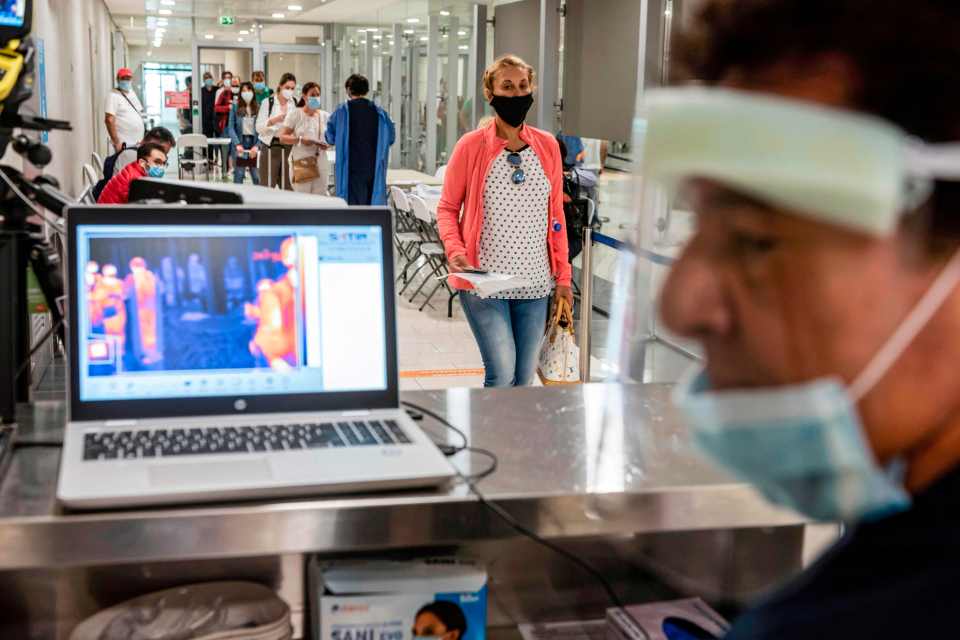 A health worker watches new arrivals on a heat-sensitive camera at  Larnaca Airport earlier this month