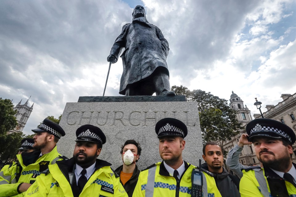 Police officers stand in front of the Winston Churchill statue during a rally in Parliament Square in London