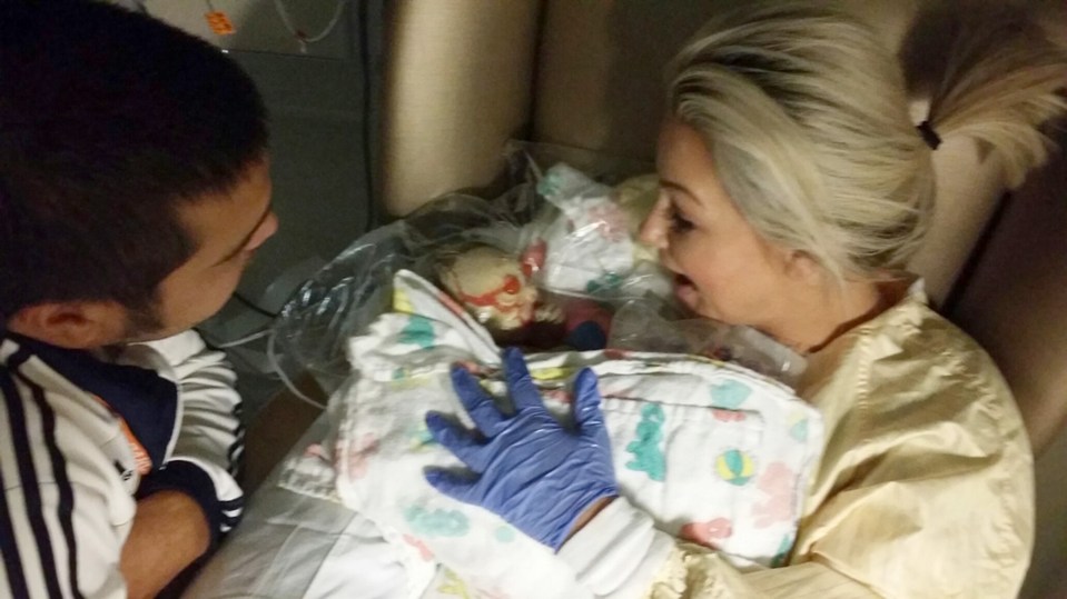 Angie is seen above cuddling Harper when she was first born, wearing blue protective gloves