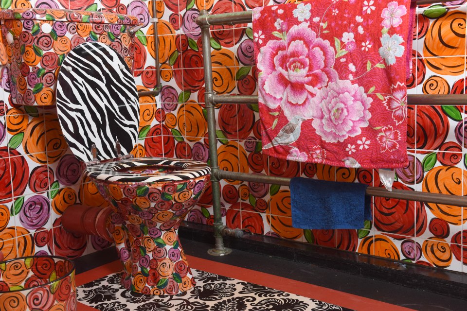 Her toilet seat has a zebra pattern while the bathroom has been painted in a distinctive style