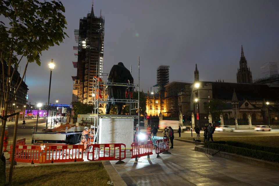 The work boarding up the statue continued into the night 