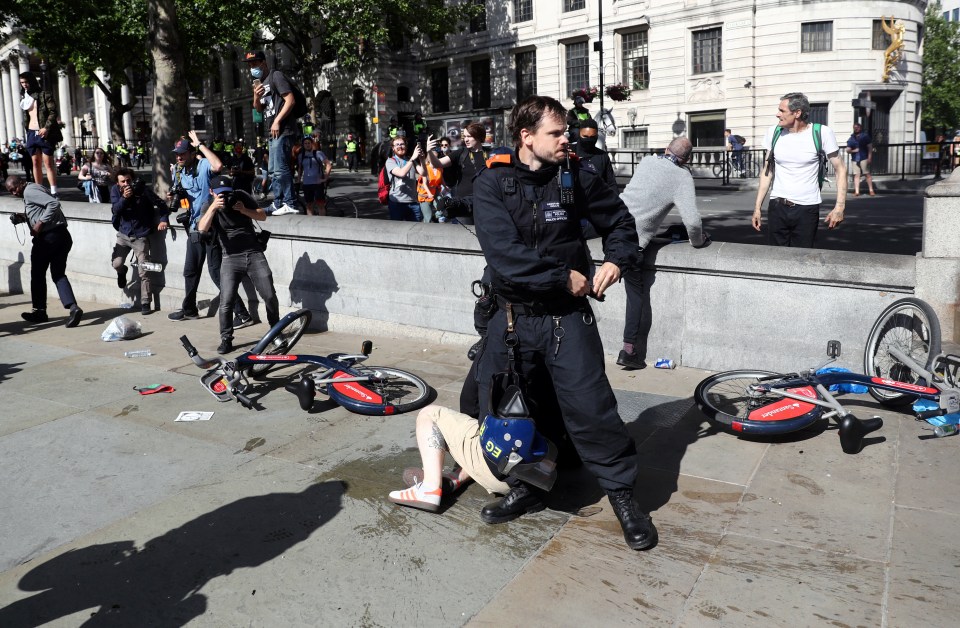 A police officer stands guard over an injured protester 