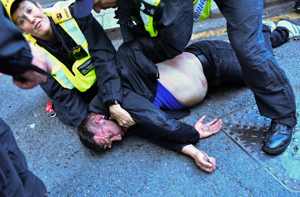 A police officer treats an injured man on the pavement