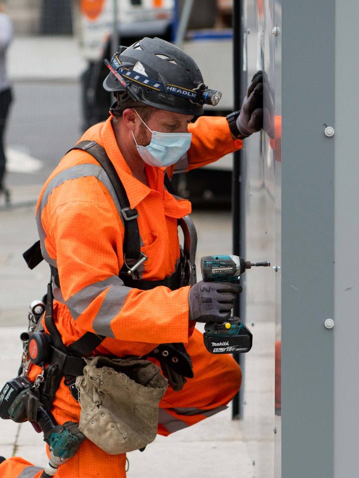 A worker starts dismantling the metal panels