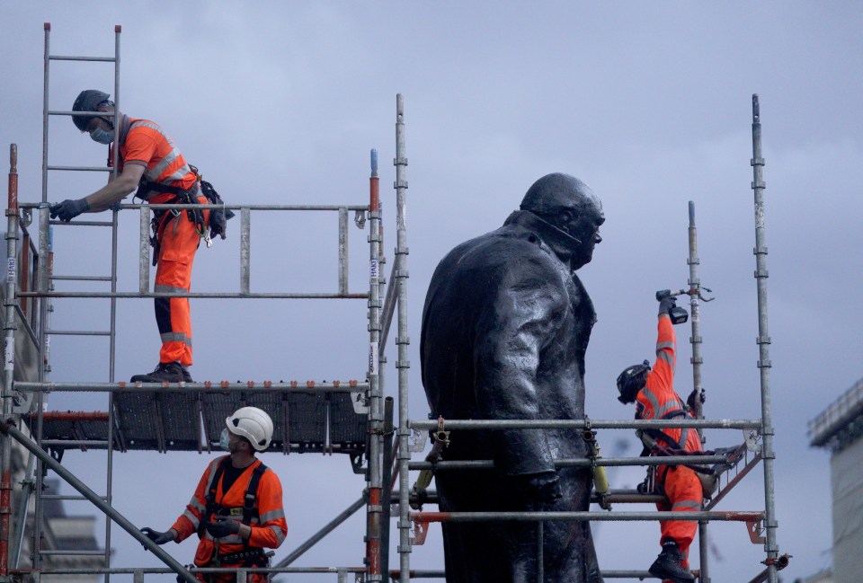 Workers take the boards off that were protecting the Winston Churchill statue from vandalism