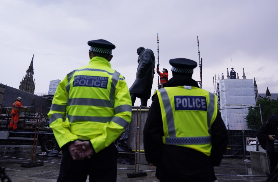 Police watch over workers taking the boards off the statue of the former Prime Minister