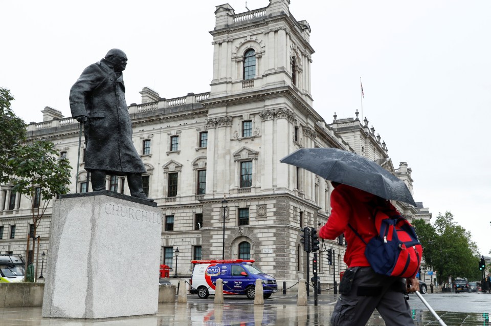 A commuter walks past the uncovered statue of Winston Churchill this morning