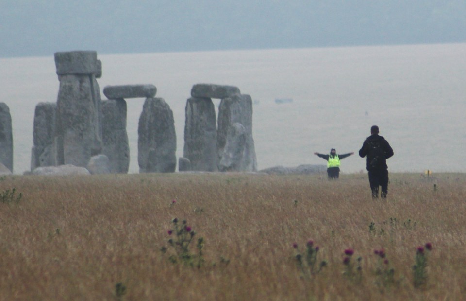 A security guard waves off a potential rule breaker approaching Stonehenge this morning