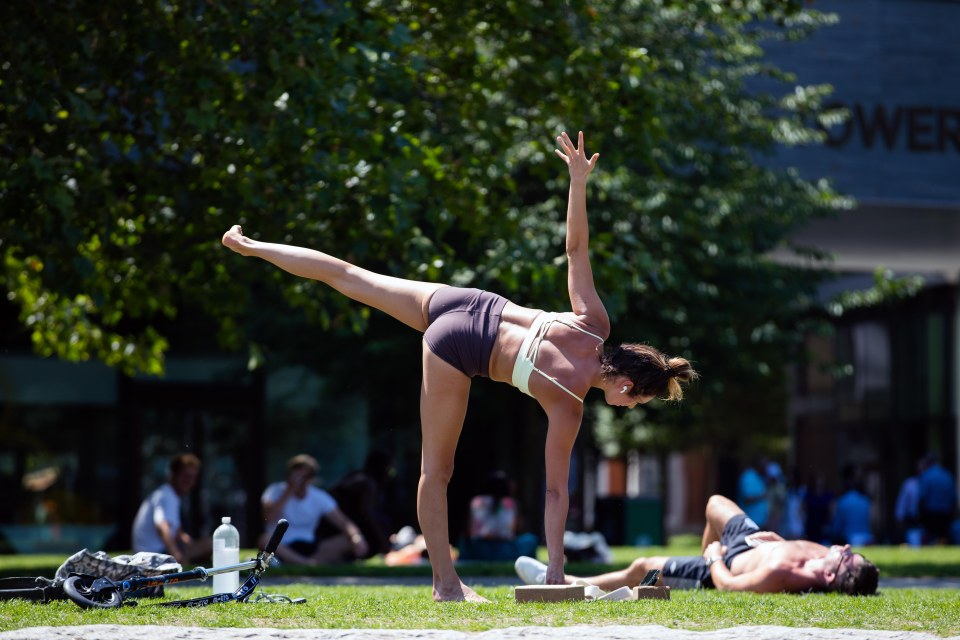 A woman performs yoga poses at Potters Field on Tuesday