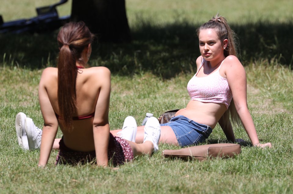 Two women enjoy the sun at Hyde Park in central London