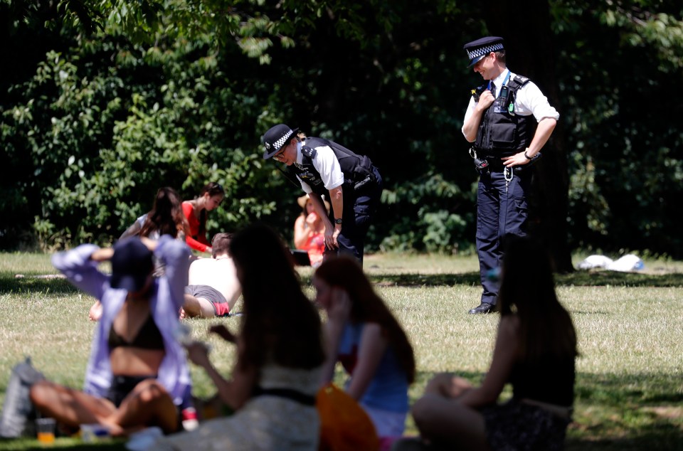 Cops speak to a sunbather at a park in London