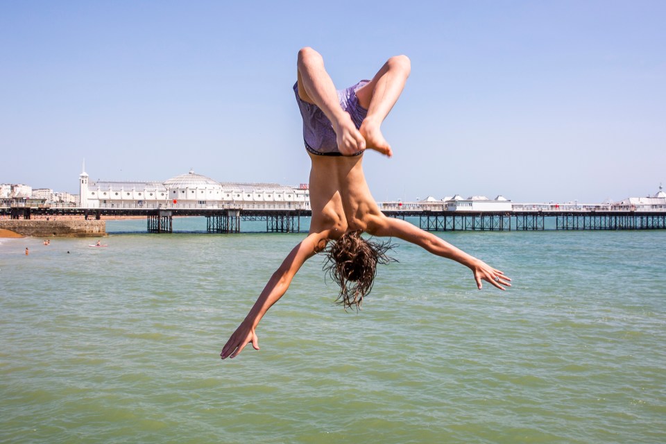 A boy leaps from a pontoon into the sea at Brighton and Hove