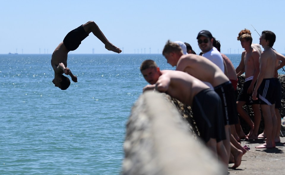 A swimmer does a back flip at Brighton beach