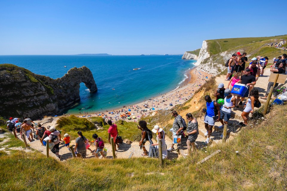 Sunseekers walk down to the water at Durdle Door