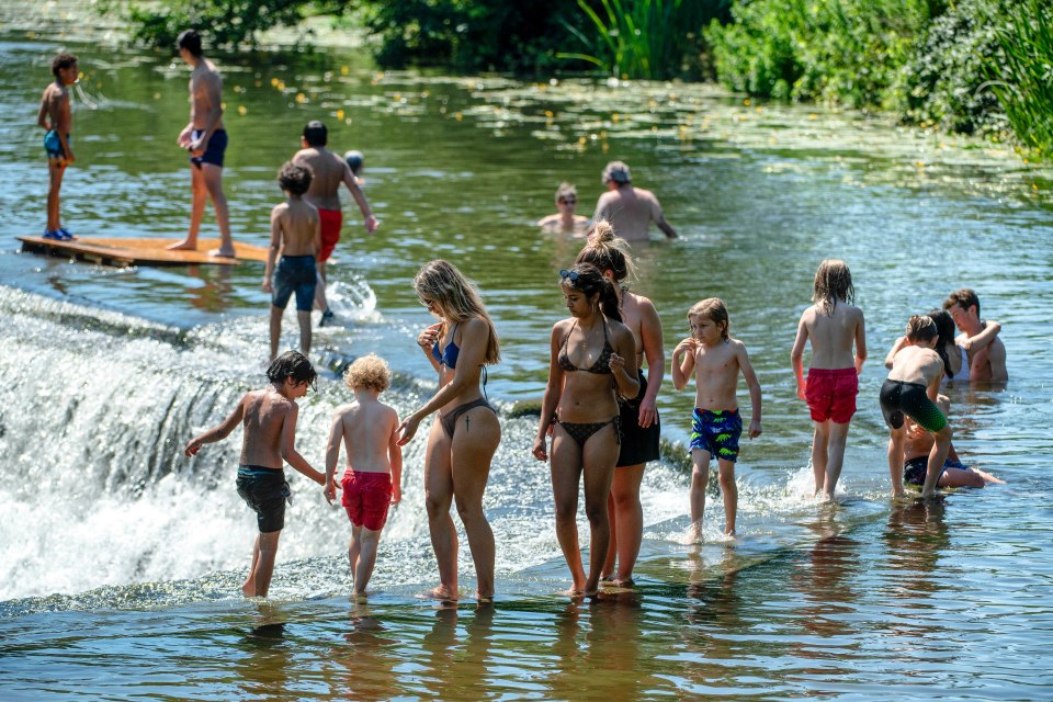 Swimmers walk around the edge of the Warleigh Weir on the River Avon near Bath