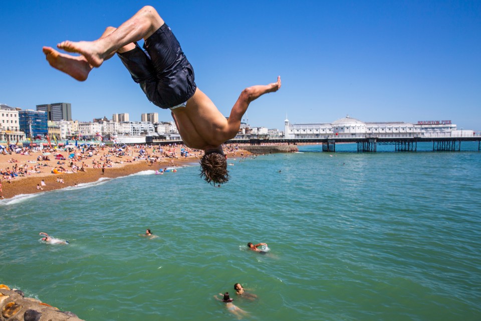 A swimmer flips into the water below at Brighton beach