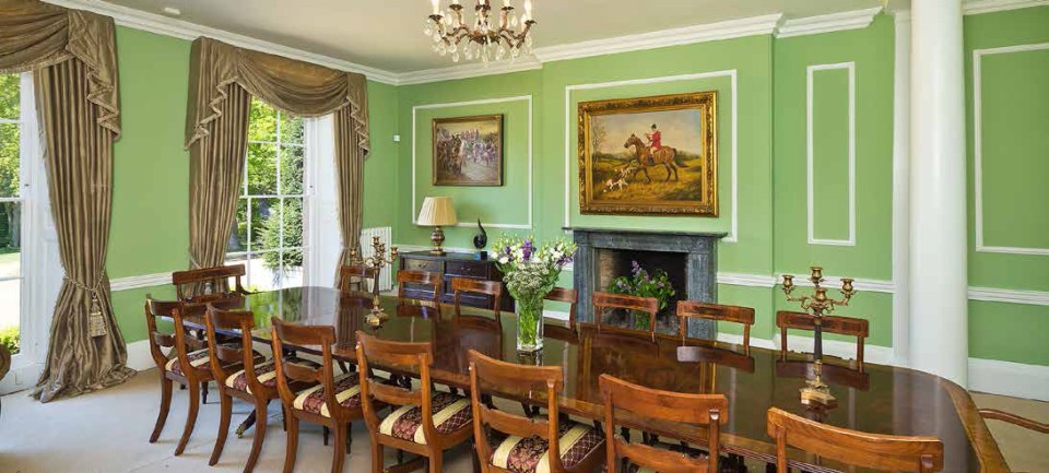 The dining room has a selection of old artwork and a sleek long wooden table