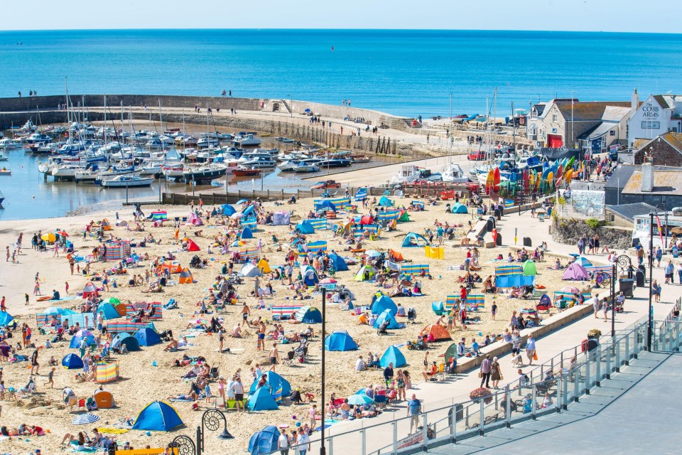 Crowds of holidaymakers flock to the packed beach at the seaside resort of Lyme Regis