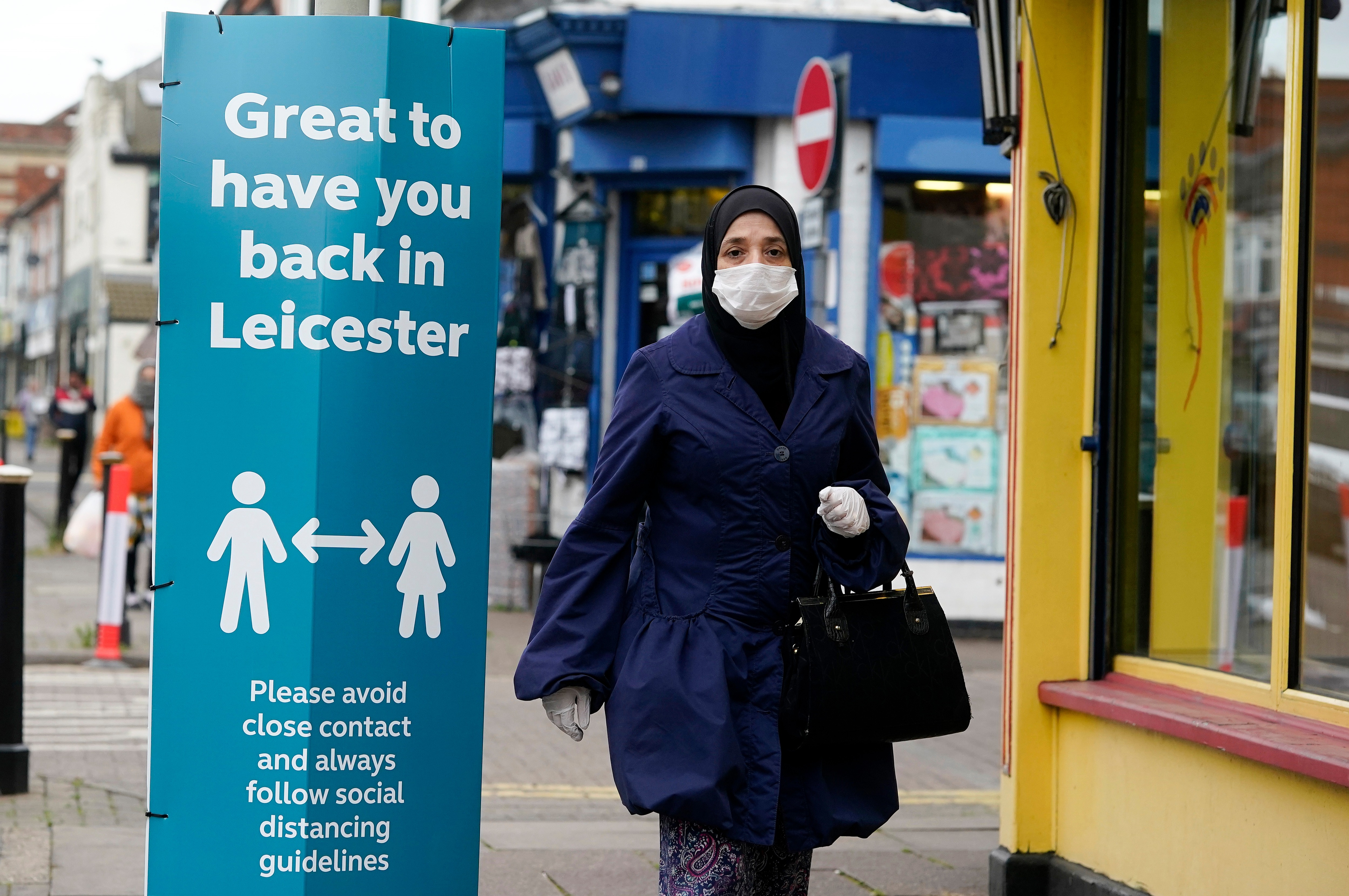 A woman walking past a sign warning about social distancing