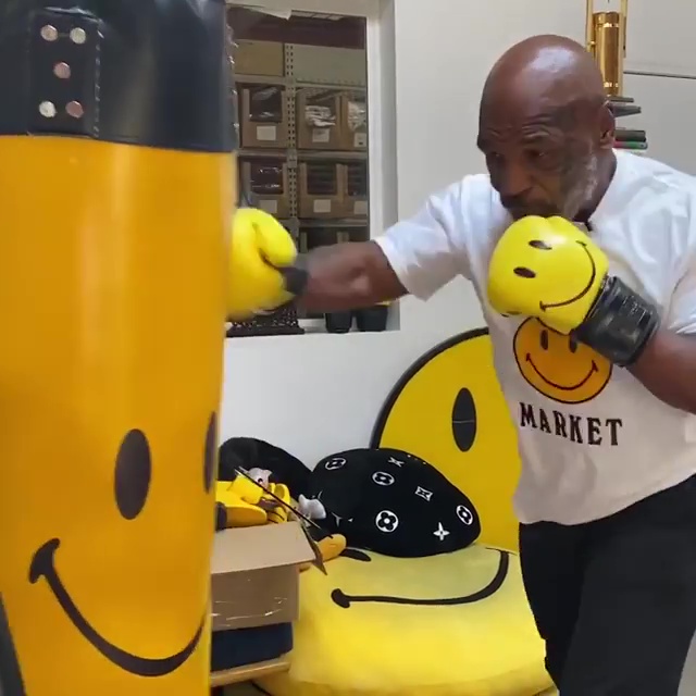 Mike Tyson released another training video battering a heavy bag with yellow smiley gloves