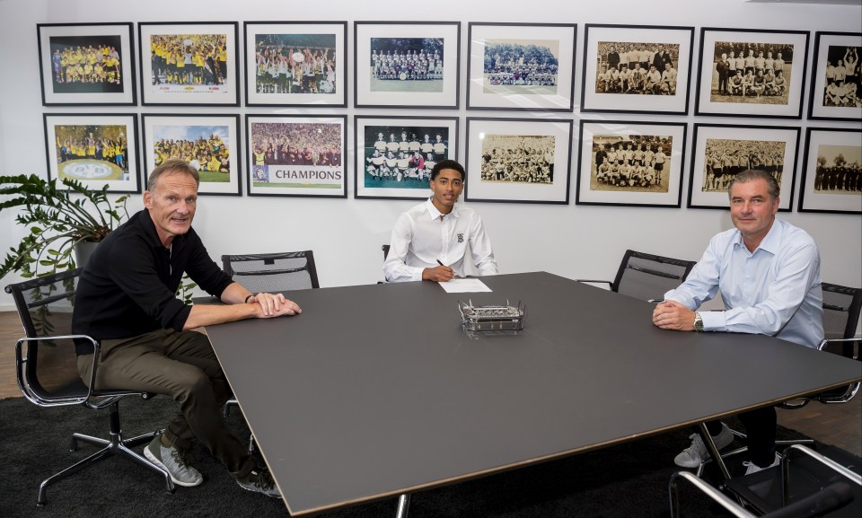 Bellingham (C) poses as he signs his contract next to Dortmund CEO Hans-Joachim Watzke (L) and sporting director Michael Zorc