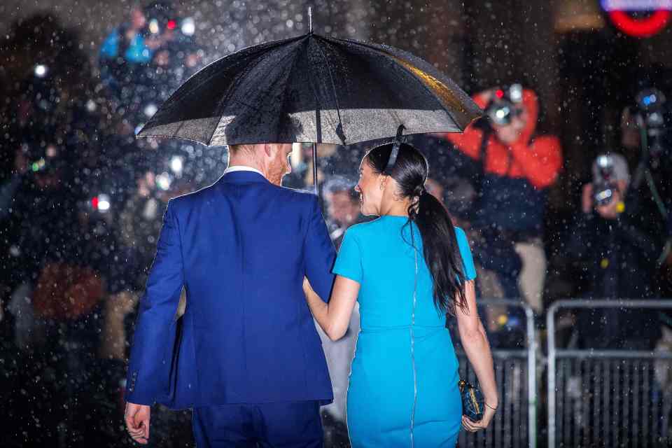 The pair laughing as they walk through the rain to an engagement