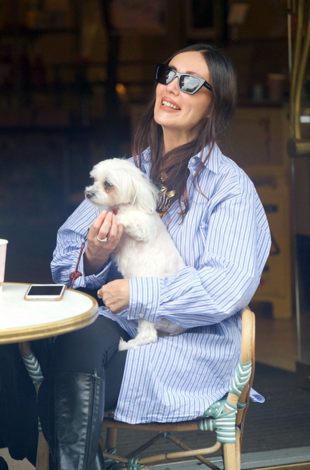 Kathy lovingly held her pet pooch as a friend stopped by for a chat while they sat at Cafe Concerto