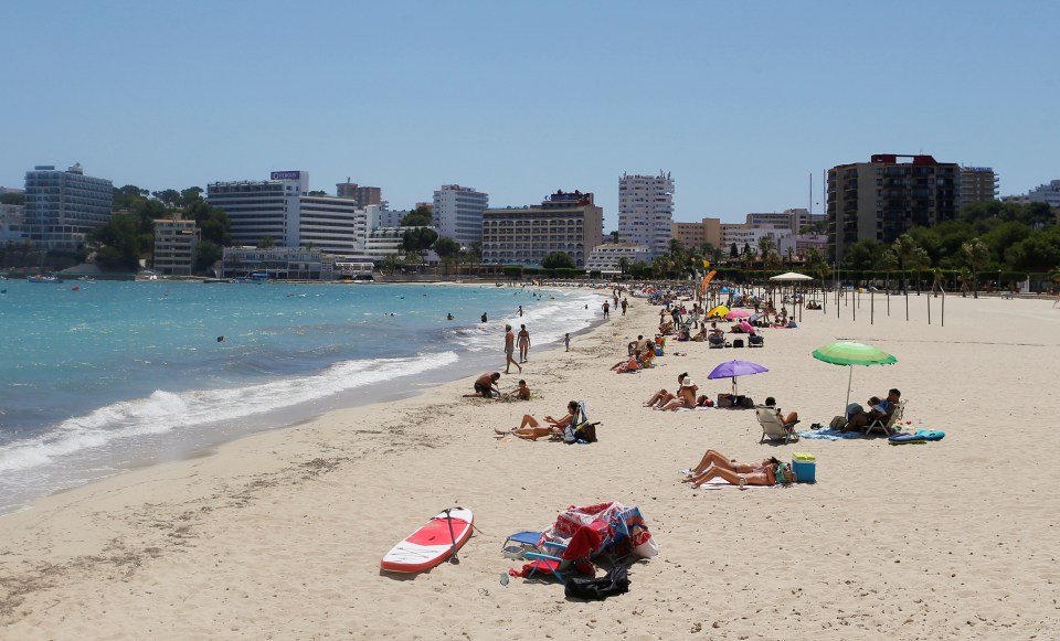 People sunbathe in Magaluf beach, which remains much quieter than usual