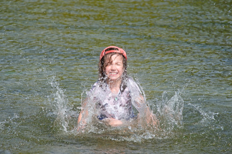 Nine-year-old Emily having a splash in the boating like to keep cool in Greenwich Park, London