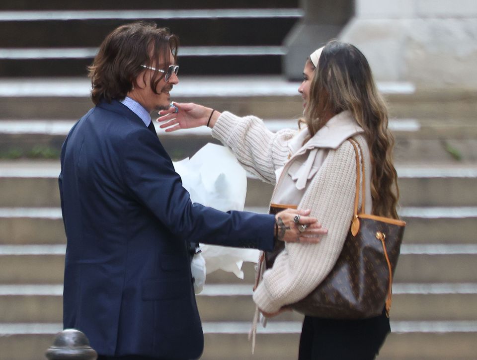 Johnny Depp gives an unknown woman a hug after receiving flowers from her outside the High Court in London today