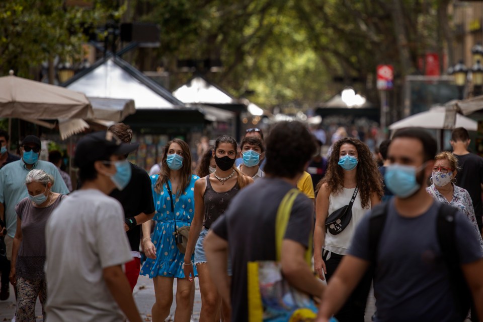 People walking down La Rambla in Barcelona wear face masks